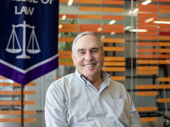 image of smiling man in front of school of law banner