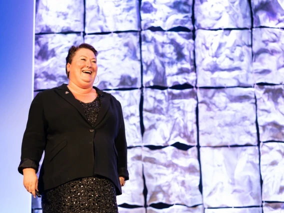 Joellen Russell presents in front of an image of the Franz Josef glacier in the Southern Alps of New Zealand