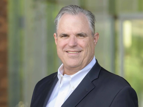 A photo of Justin Starren, smiling in a casual pose, wearing a white button down shirt and jacket