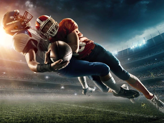 A football player tackling another football player who is holding a ball