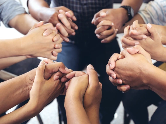 Close-up image of several people holding hands 
