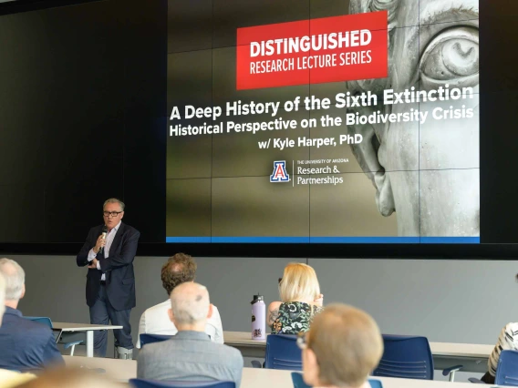 View from the back of a lecture hall over the heads of the audience with a projection of a face from a classic marble sculpture and text that reads, “Distinguished Research Lecture Series”. 