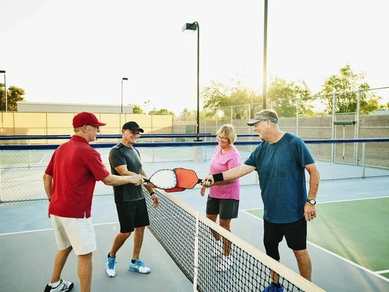 Four older people playing pickleball