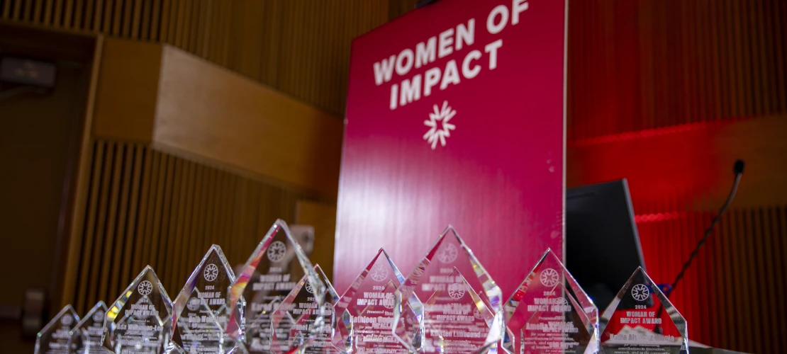 A table of awards in front of a red banner.