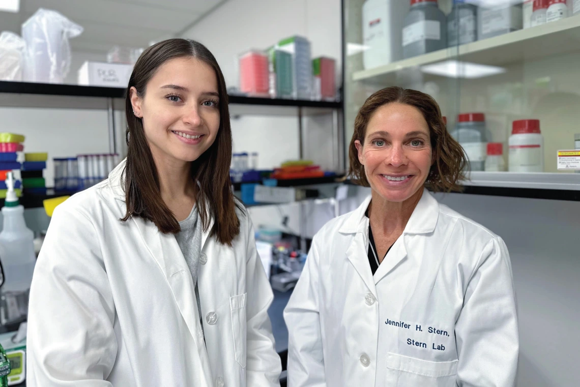 Jennifer Stern and Kassandra Bruner, wearing white coats in a lab setting