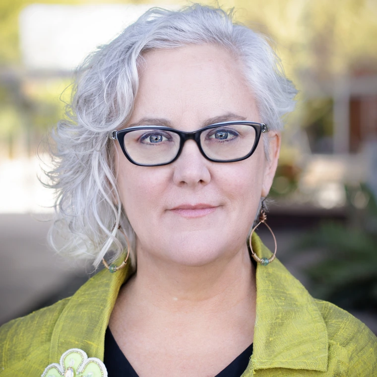 woman with wavy white hair in black glasses and chartreuse blazer