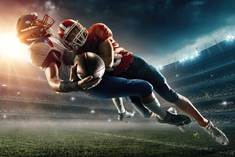 A football player tackling another football player who is holding a ball